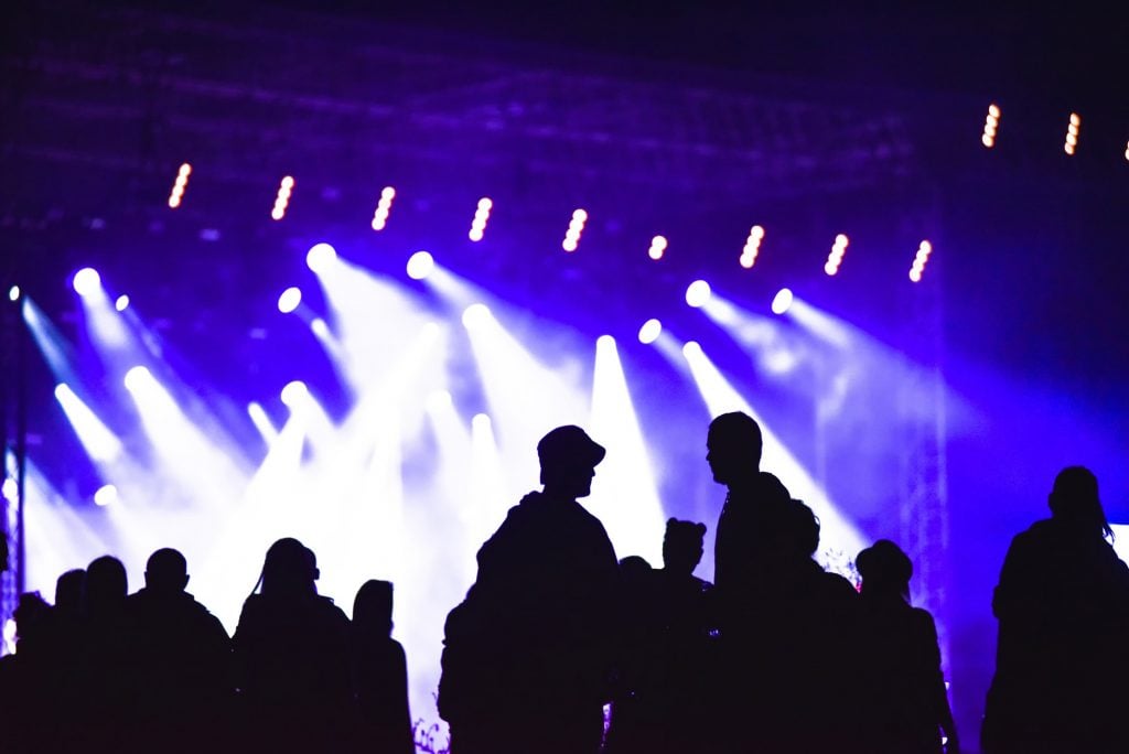 Group of friends enjoying music festival together. Silhouette of friends socializing at a concert